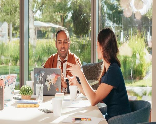 Two people having a discussion over coffee in a bright meeting room